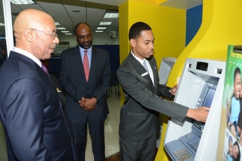 Governor-General, His Excellency Sir Patrick Allen (foreground) and Earl Jarrett (centre), JNBS General Manager, get banking information on the JN Express banking centre from Bryan Robinson, Member Service Representative from the Half-Way-Tree Branch in St. Andrew. 