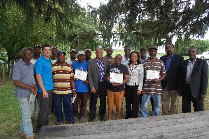 Minister of Labour and Social Security, the Hon. Derrick Kellier (center), along with Permanent Secretary in the Ministry of Labour and Social Security, Mrs. Colette Roberts-Risden (fourth from right), pose for a photograph with farm workers from M.G. Hurd Farm, Hudson Valley, New York. The farm workers were presented with the Prime Minister’s certificate of appreciation for their long serving participation in the United States Jamaica Seasonal Agriculture H2A Programme (Farm Worker Programme). The presentation was held on Wednesday, August 19, 2015 in Hudson Valley, New York. (Photo Credit to Derrick Scott)