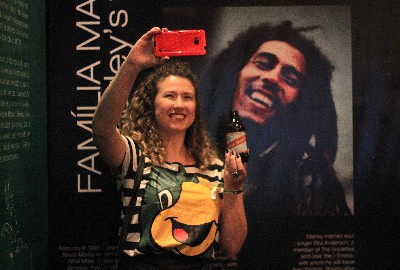 Jamaica House visitor enjoys a Red Stripe Beer while snapping a selfie with Bob Marley,