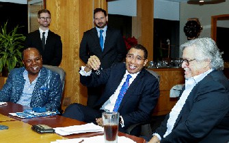 Prime Minister the Most Hon. Andrew Holness (seated , centre) shares a light moment with Minister of Tourism, Hon. Edmund Bartlett (left) and Chairman of Carnival Corporation, Micky Arison.