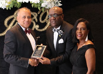 Derrick Scott (center), receives a plaque from President of Integrity Children’s Fund (ICF), Major Karl Chambers, in recognition of his support to the organization.  At right is Mrs. Marcia Chambers.  